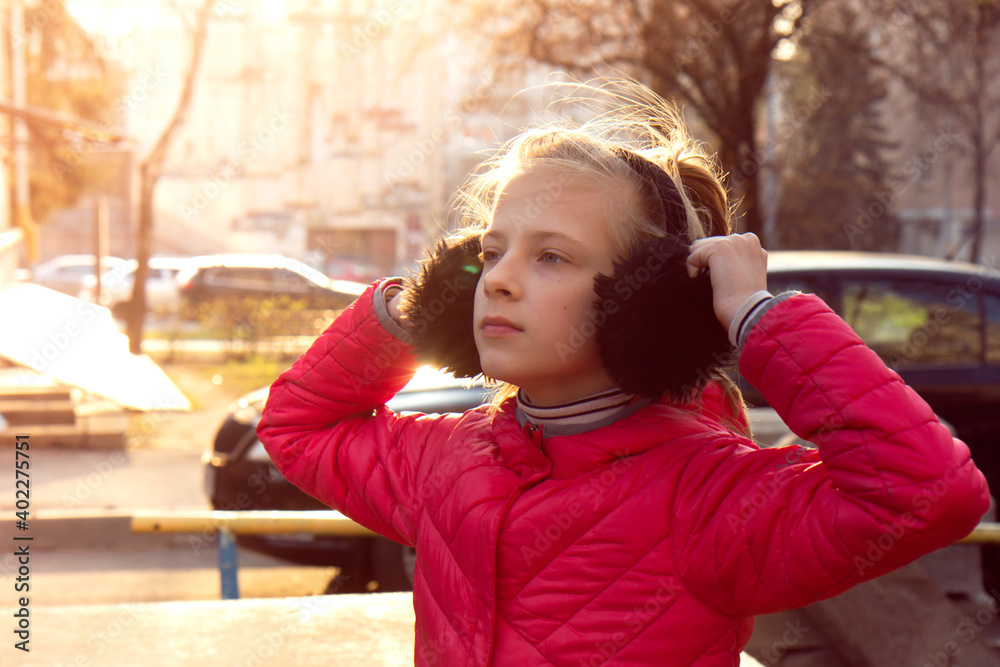 Teenager girl in warm earmuffs on the street. Lifestyle