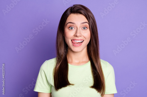 Close-up portrait of attractive cheerful funny brown-haired girl licking lip isolated over bright violet color background © deagreez