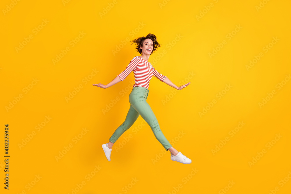 Full length body size profile side view of lovely cheery girl jumping going isolated over bright yellow color background
