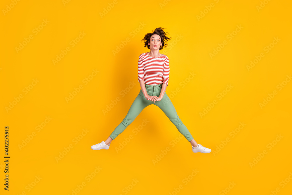 Full length body size view of lovely skinny funky girl jumping having fun sending air kiss isolated over vivid yellow color background Full length body size view of lovely skinny funky girl jumping having fun sending air kiss isolated over vivid yellow color background