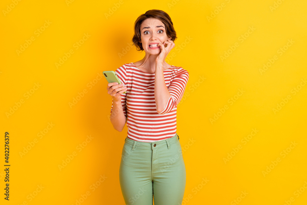 Portrait of frightened lady staring bite nail stressed look bad news isolated on yellow color background