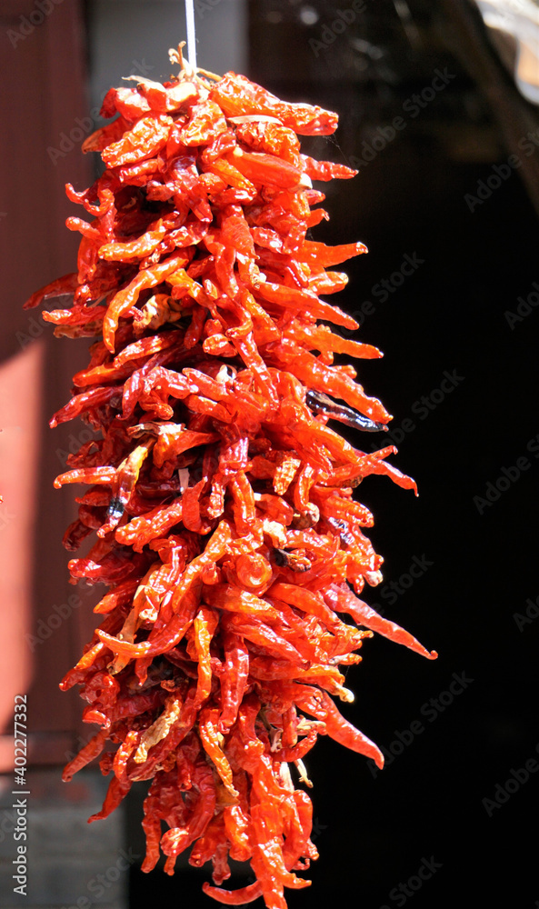 Red chili peppers dried hanging on a traditional building entrance ...