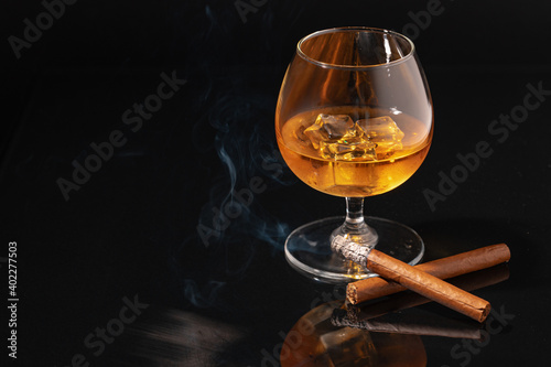 Canvas Print Glass of whisky and lighted cigar on black background