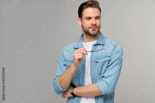 Portrait of young handsome caucasian man in jeans shirt over light background