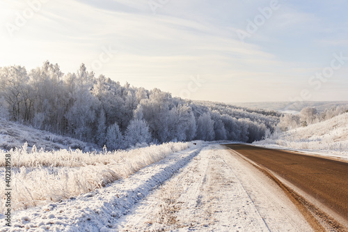 Winter panorama on the road through the snowy forest