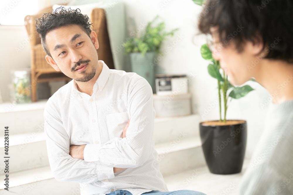 部下の転職相談を聞いて判断を迷って腕を組んでいる中年のヒゲの日本人男性 部下の転職相談を聞いて判断を迷って腕を組んでいる中年のヒゲの日本人男性