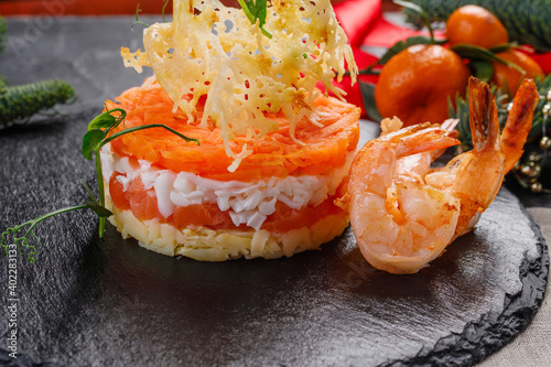 salad with salmon and tiger shrimps on a dark stone plate. Salad on the New Year's table
