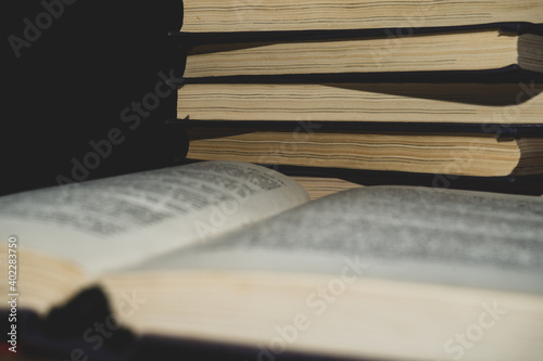 the book is open in the middle of the pages against the background of a stack of books.