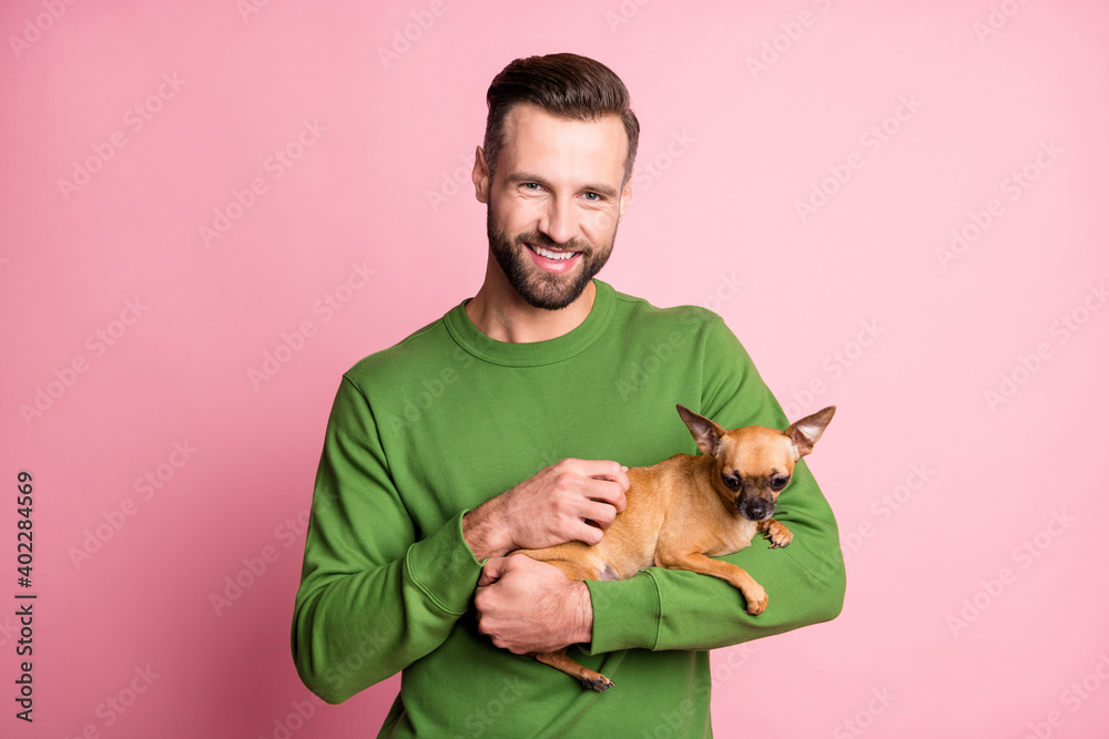 Obraz premium Photo portrait of happy cheerful man keeping small best friend brown dog isolated pastel pink color background