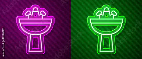 Glowing neon line Washbasin with water tap icon isolated on purple and green background. Vector.