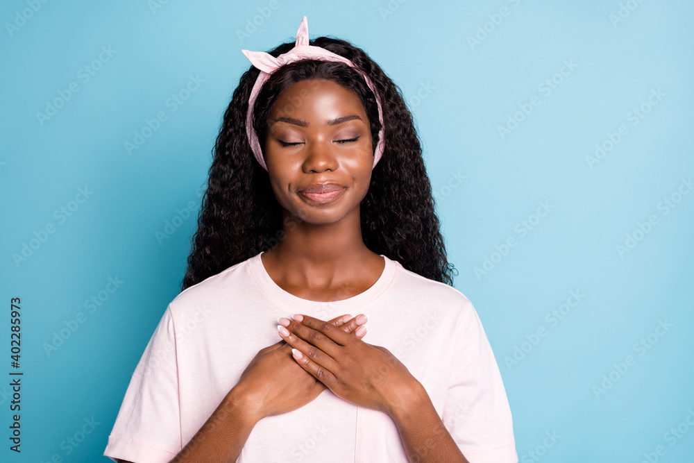 Close-up portrait of pretty dreamy wavy-haired girl putting palms on chest enjoying silence isolated over blue pastel color background - obrazy, fototapety, plakaty 