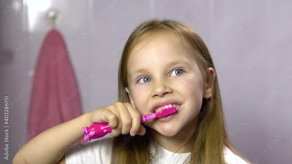 Little blonde girl brushes her teeth in the bathroom.Close-up.A 4-5 year old girl is brushing her teeth with a pink toothbrush.4k Little blonde girl brushes her teeth in the bathroom.Close-up.A 4-5 year old girl is brushing her teeth with a pink toothbrush.4k