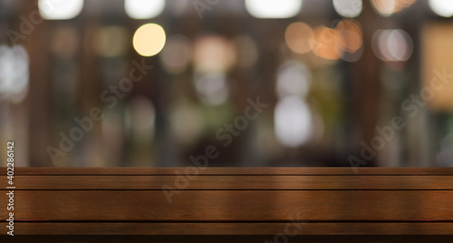 Empty wooden table top with lights bokeh on blur restaurant background.