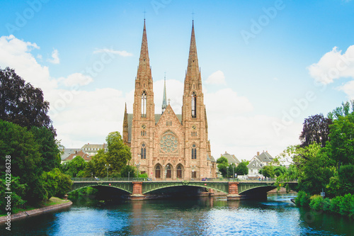 Scenic view of St. Paul's Church and a bridge that leads over the Ill river in the city of Strasbourg, France under a clear blue sky.