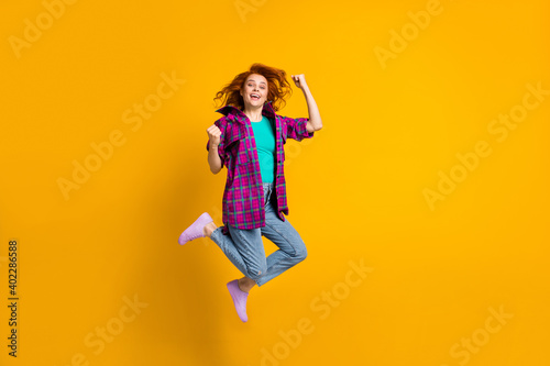 Full body photo of delighted carefree lady fists up checkered purple long shirt isolated on yellow color background © deagreez