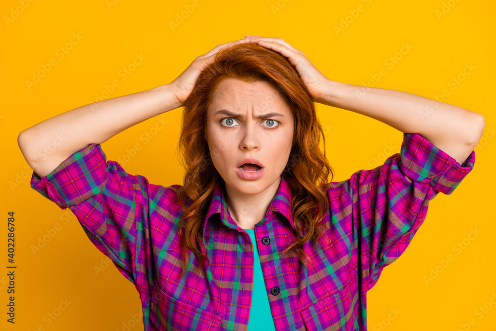 Photo of impressed worried lady hands on head open mouth staring wear checkered isolated on yellow color background Photo of impressed worried lady hands on head open mouth staring wear checkered isolated on yellow color background
