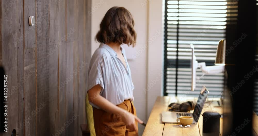 Young woman controlling room temperature with a smart thermostat at home. Medium shot. Smart home and smart heating system concept