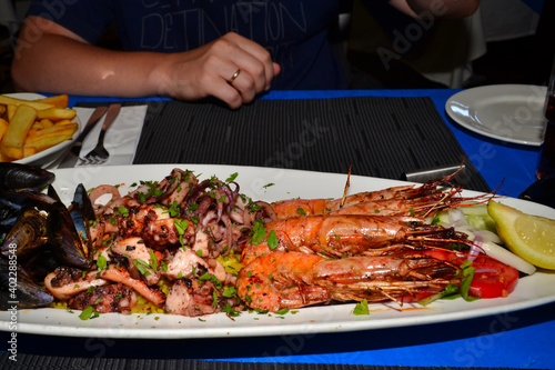Delicious seafood platter from Malta  - freshly caught and grilled octopus tentacles, calamari rings in tempura, giant shrimps, clams, fish fillets and mussels 