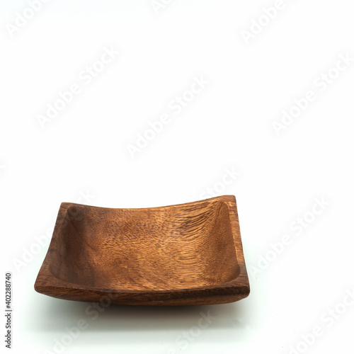 This square plate is made from a single piece of natural wood. Brown color. The texture is visible. Isolated on white background. Lower left corner.