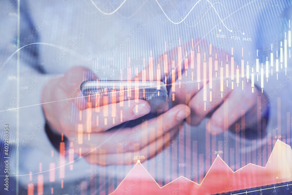 Double exposure of man's hands holding and using a digital device and forex graph drawing. Financial market concept.