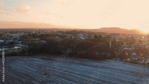 4K Aerial reveal of beautiful sunset over Cheshire, England, Winter 2020. Rural farmland, small villages and a castle on a hill in the background photo