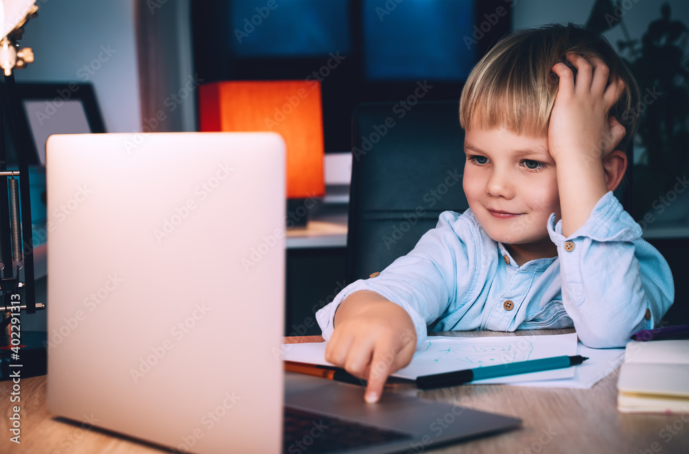 School boy with laptop at table in evening at home. School boy with laptop at table in evening at home.