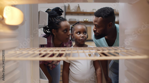 фотографія Afro-american hungry family looking into empty fridge at home
