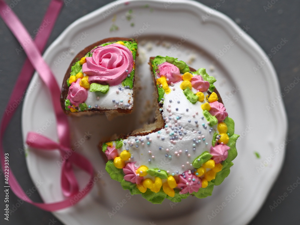 Top view of Easter cakes on a gray background. A piece of bun is cut off for a treat.A festive pastry shop with a pink ribbon in the background.