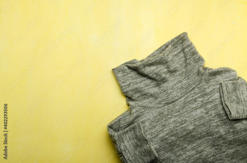 Fototapeta premium Trendy colored grey sweater on the bright yellow background.Empty space