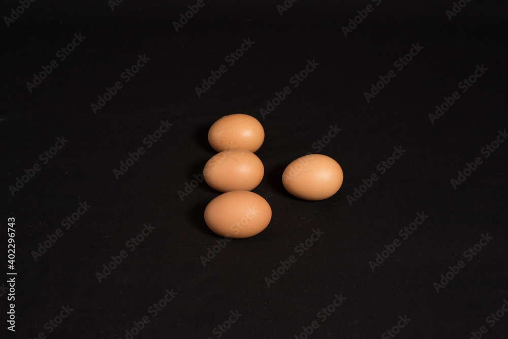 High angle shot and top view of four eggs isolated on black background. High angle shot and top view of four eggs isolated on black background.