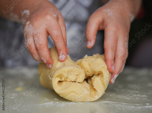 Girl hands cooks cookie dough. She mixes butter, powdered sugar and flour. Family, children holiday concept. Selective focus.