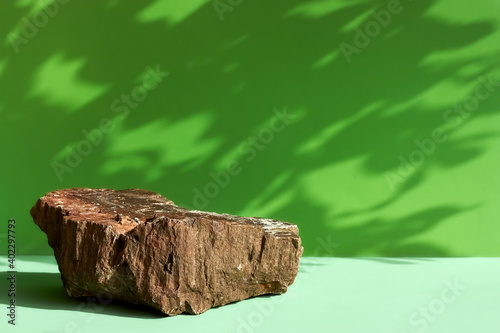 Natural stone podium display with leaf shadow. Product presentati on soft green background. Cosmetics or beauty product promotion minimalist mockup.