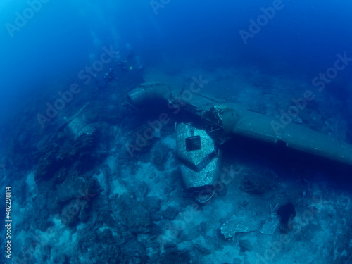 scuba divers exploring airplane wreck underwater taking photos of c47 dakota airplane engine 