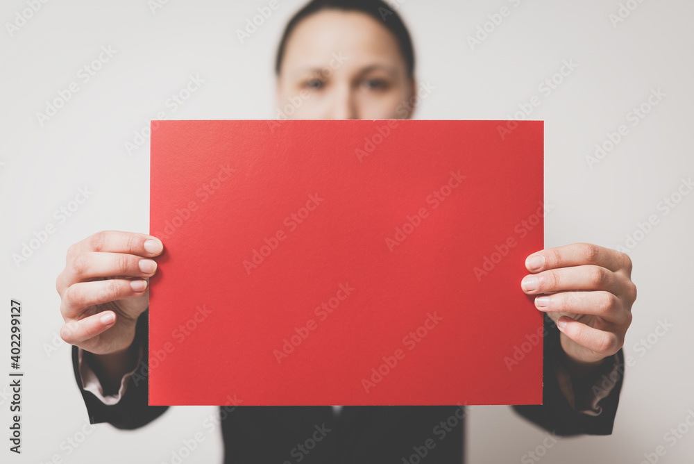 A woman in a business dress code holds a red horizontal empty signboard with two hands. Copy space with close-up. A woman in a business dress code holds a red horizontal empty signboard with two hands. Copy space with close-up.