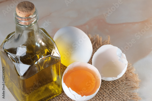 White raw eggs lie next to olive oil