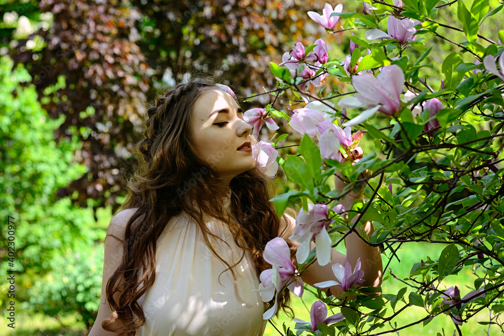 Portrait of young attractive woman in spring garden with blooming magnolias. Spring background. Woman's Day. Greeting card. Portrait of young attractive woman in spring garden with blooming magnolias. Spring background. Woman's Day. Greeting card.