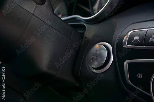 Engine start stop button in a car with keyless go. Light control panel in foreground. © Ethan L