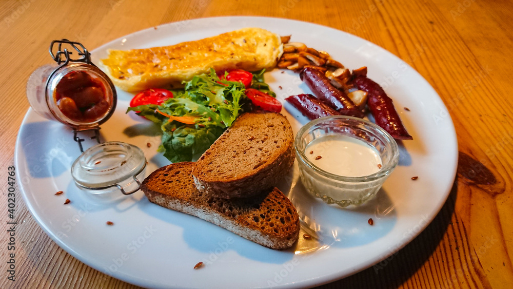 A delicious and delicious breakfast of fried eggs, sausages, champignons as well as lettuce and tomatoes A delicious and delicious breakfast of fried eggs, sausages, champignons as well as lettuce and tomatoes