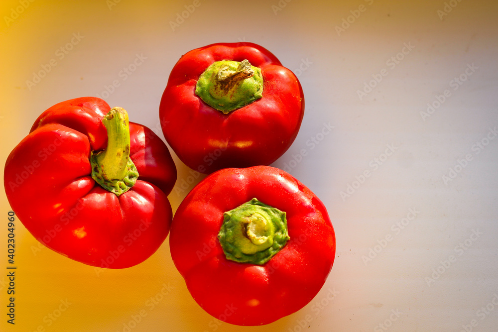 Several juicy red bell peppers lie in the rays of the sun Several juicy red bell peppers lie in the rays of the sun