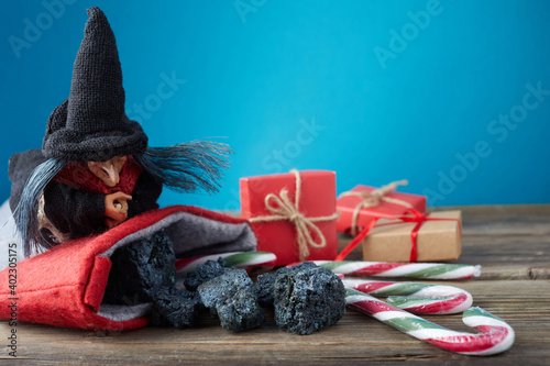 The Befana with sweet coal and candy on wooden background. Italian Epiphany day tradition. photo
