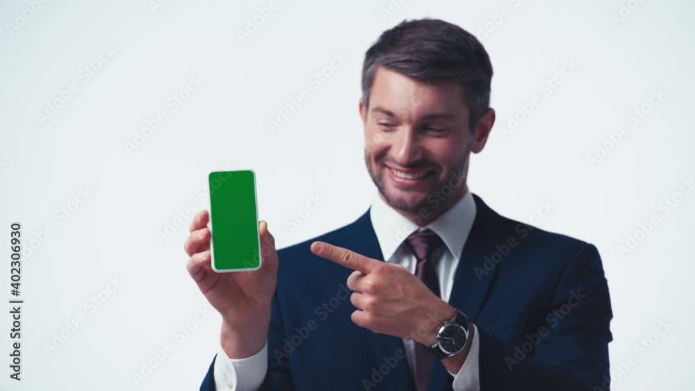 cheerful businessman pointing at smartphone with green screen isolated on white cheerful businessman pointing at smartphone with green screen isolated on white