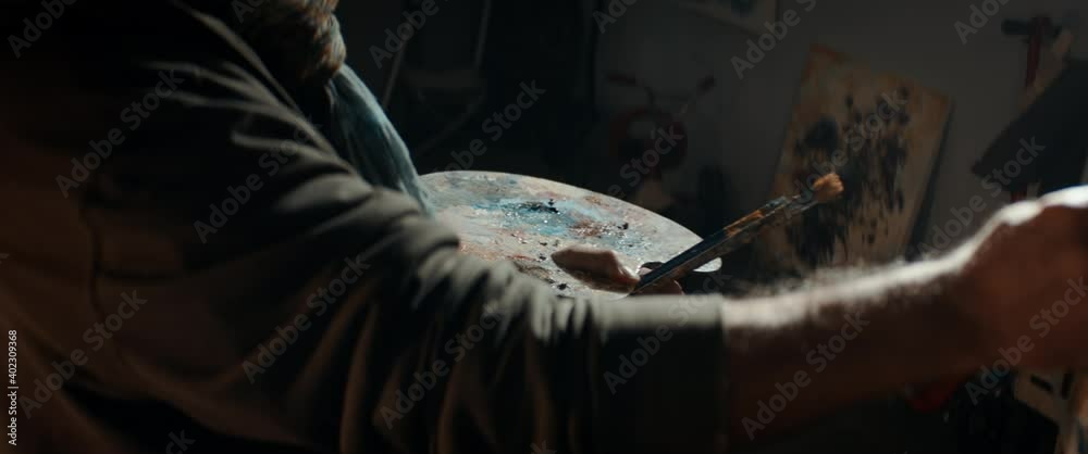 CU Unrecognizable senior artist working on his painting in his garage studio. COVID-19 self isolation new hobbies concept. Shot with 2x anamorphic lens