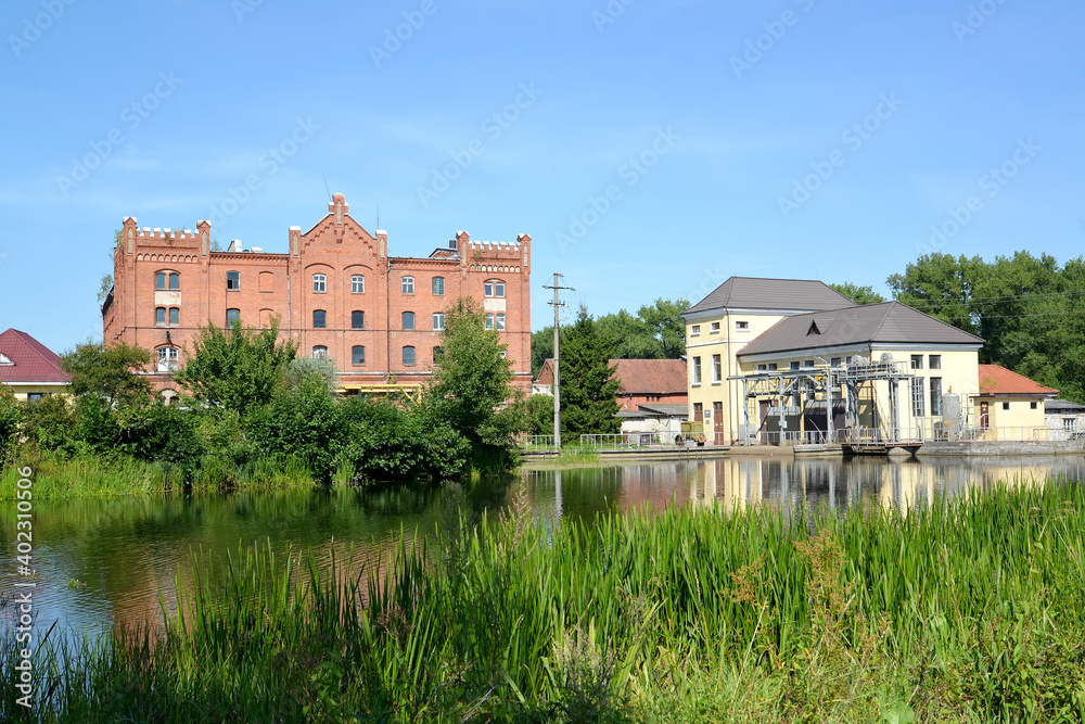 View of the Vikhert mill and the building of the engine hall of the Ozerskaya hydroelectric station on the Angrap River. Ozersk, Kaliningrad region