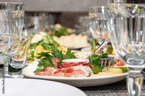 Festive table setting, family dinner with served italian antipasti - marinated salmon, hamon, Carpaccio, pear, basil. Tablescape.