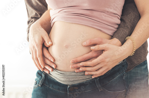 Happy mother and father are hugging pregnant tummy, close up © Patrick Daxenbichler