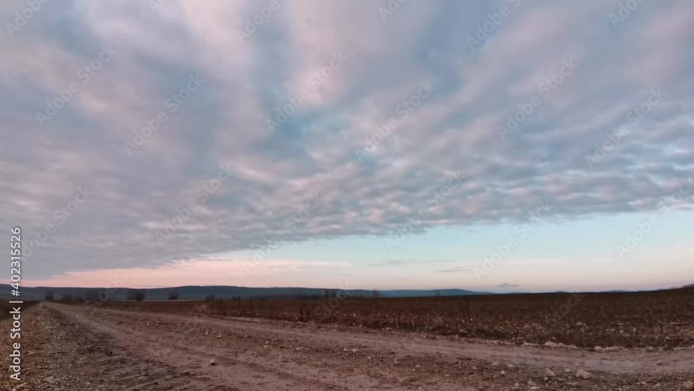 Enermous cloud with sharp edge timelapse over a muddy road and plough field with hills in the background (4K, 30FPS) Enermous cloud with sharp edge timelapse over a muddy road and plough field with hills in the background (4K, 30FPS)