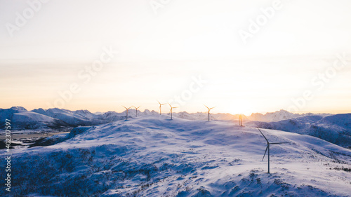 Wind turbines on snowy ridges at glowing sundown