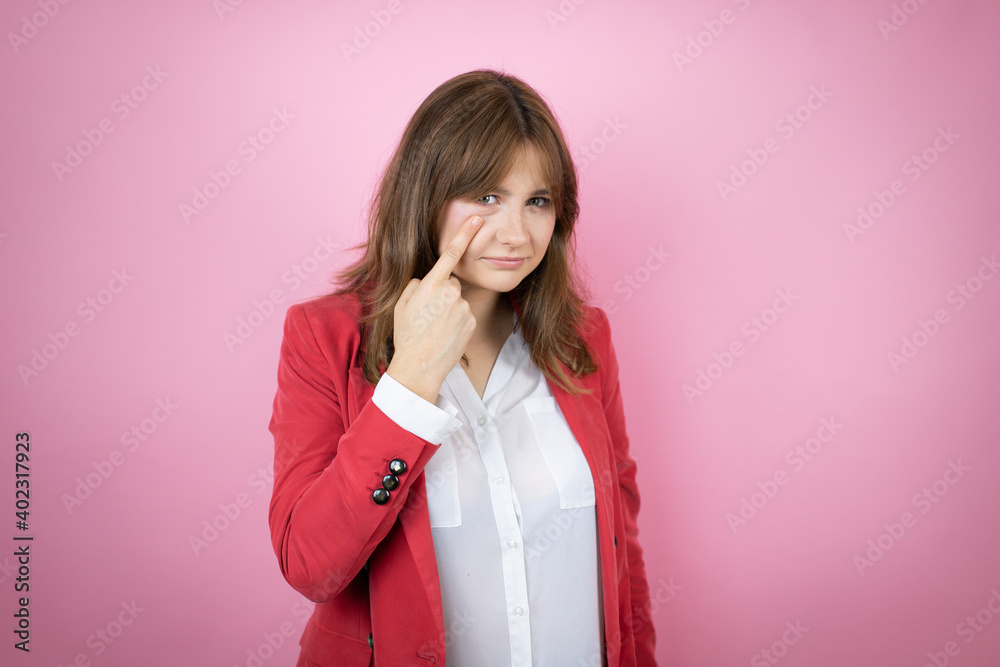 Young business woman over isolated pink background Pointing to the eye watching you gesture, suspicious expression