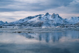 Snowy mountains on seashore with glaciers at sunset