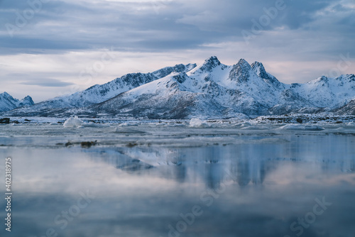 Snowy mountains on seashore with glaciers at sunset